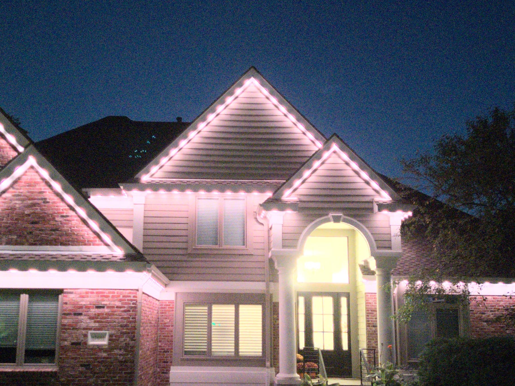 Close view of a Brytr channel tucked into the fascia of an Omaha home, individual warm white LEDs visible along every gable and eave