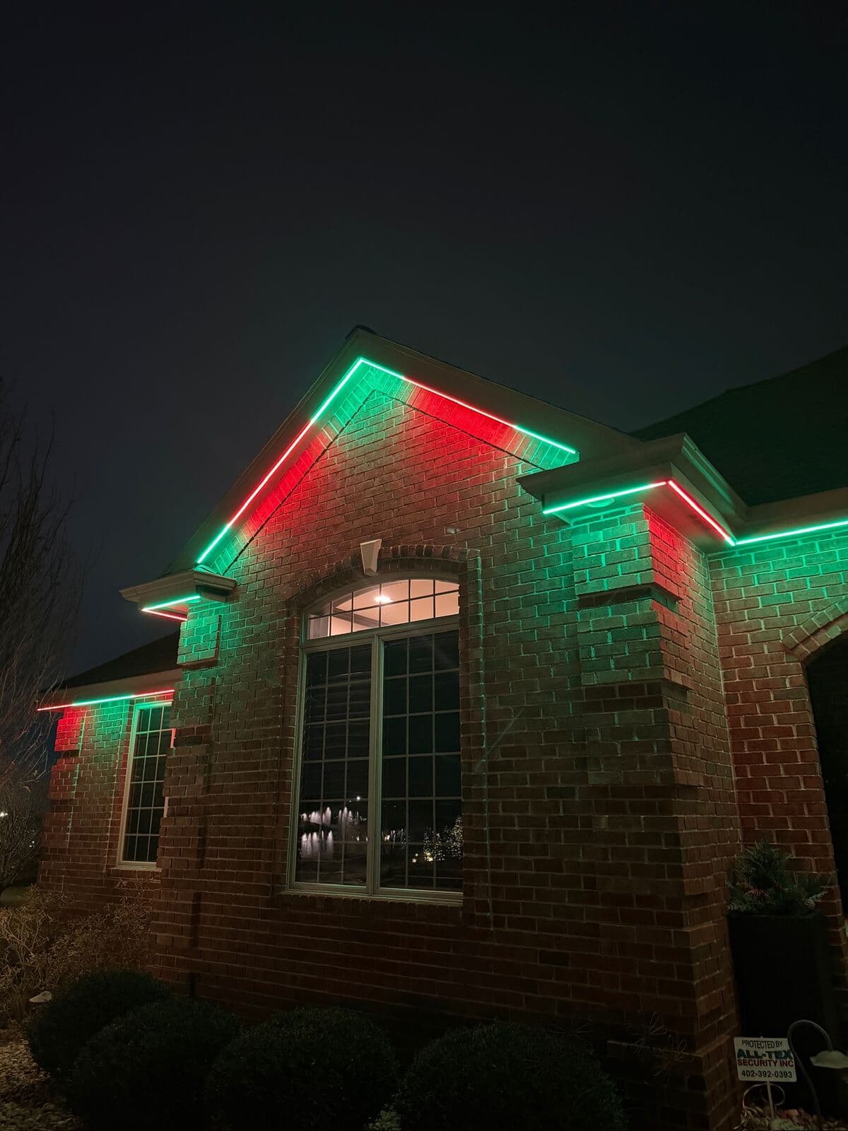 Red and green alternating along the gable and eave of a brick Omaha home, close enough to see each point