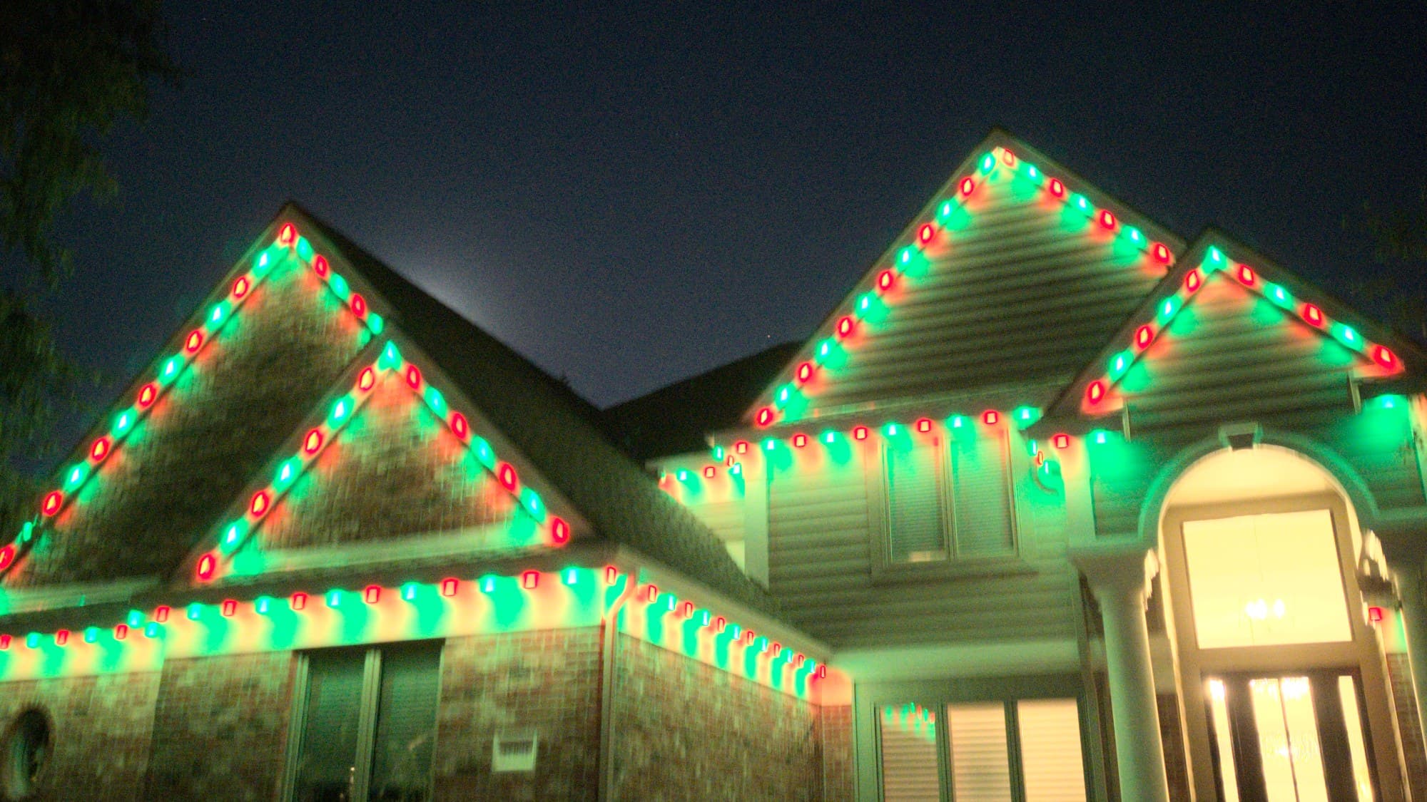 Permanent Christmas lights alternating red and green bulbs along every roofline of an Omaha home