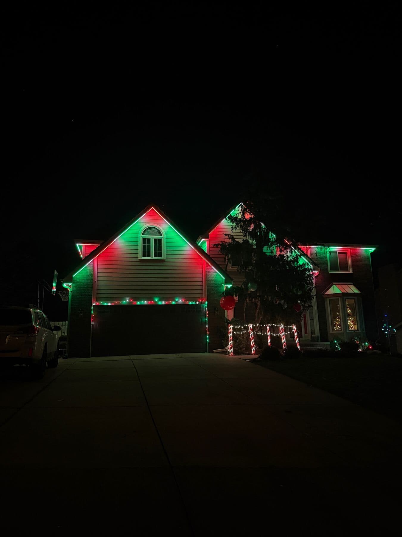 An Omaha two-story in red and green with lit wreaths in the windows and net lights over the shrubs