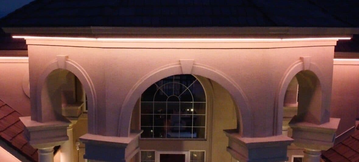 The same stucco turret after dark, one continuous warm run following every facet of the octagon