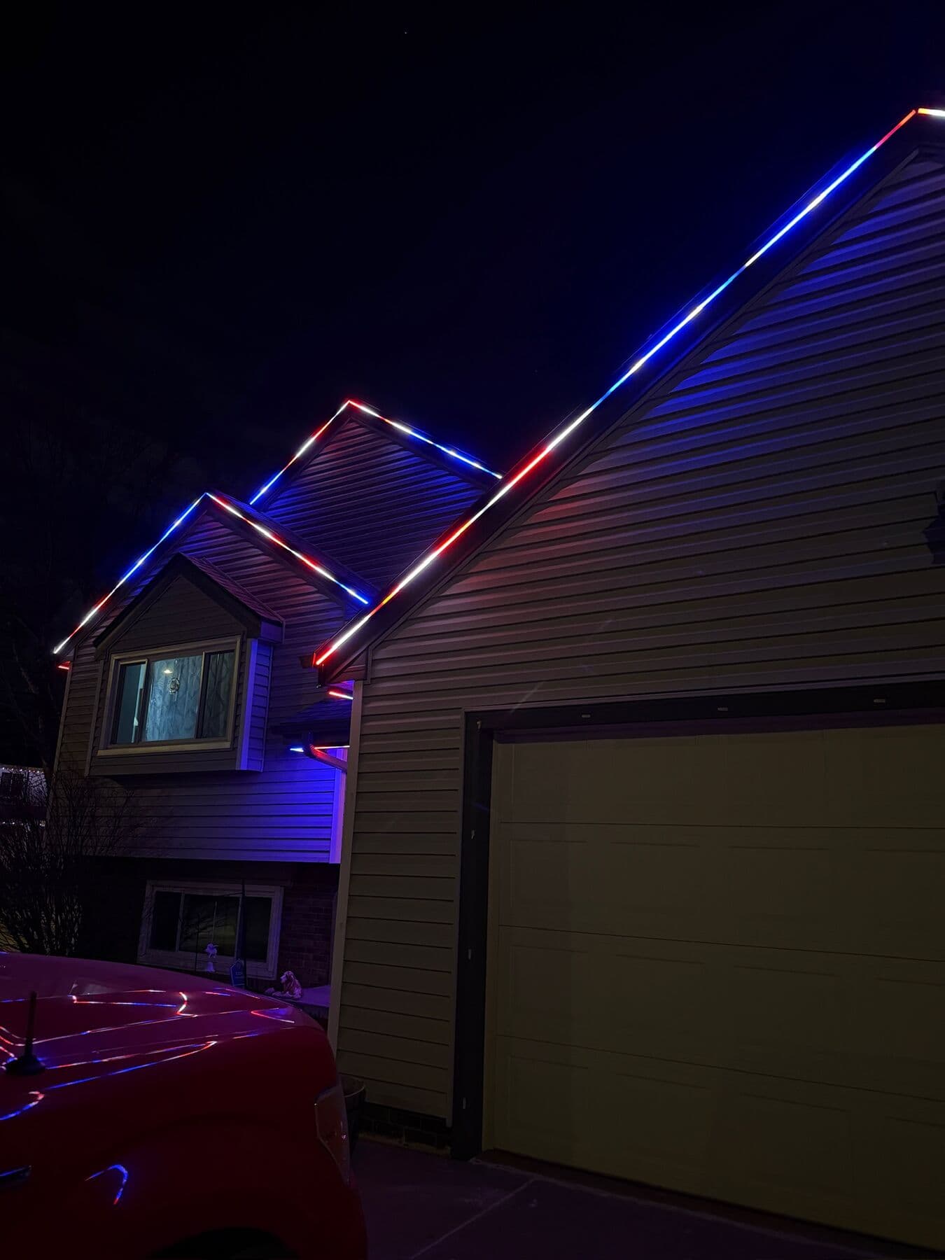 Red, white and blue running along the rake and gable lines of an Omaha home against a dusk sky