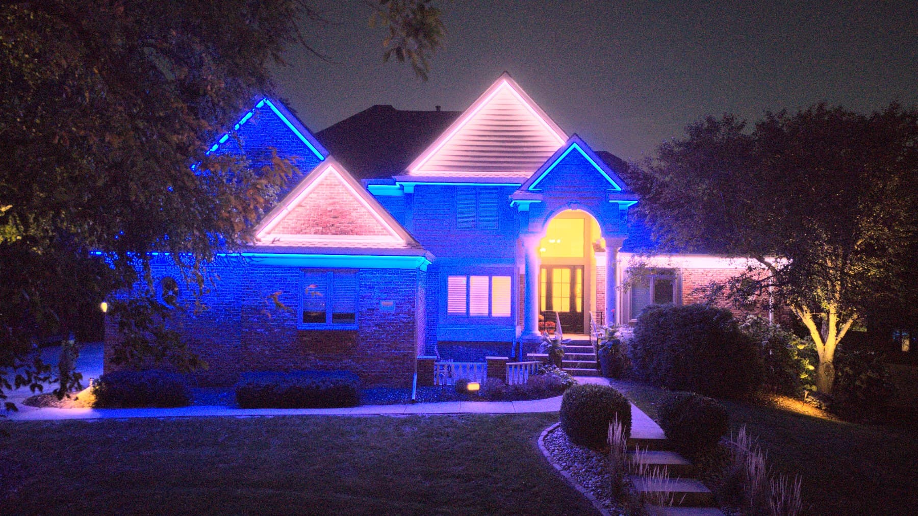 An Omaha home in blue and white with landscape uplighting