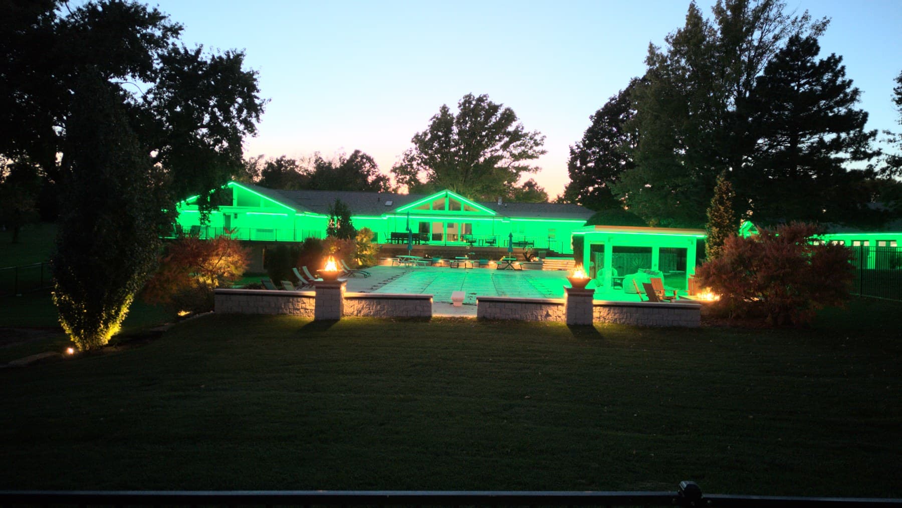 An Omaha home and pool deck lit green at dusk