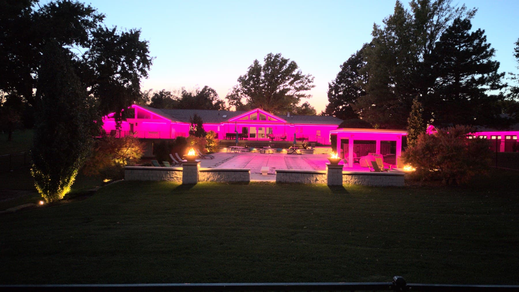 An Omaha home and pool deck lit pink at dusk