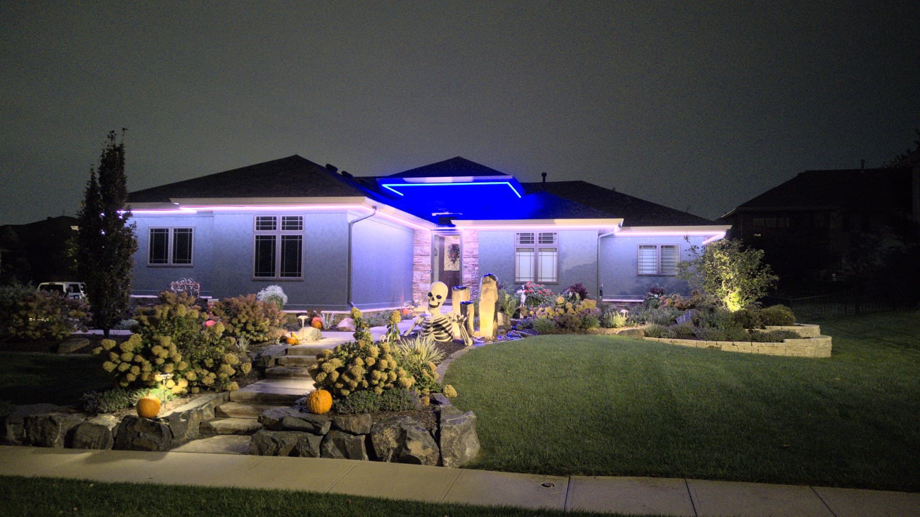 A long Omaha ranch elevation lit blue and white with landscape uplighting