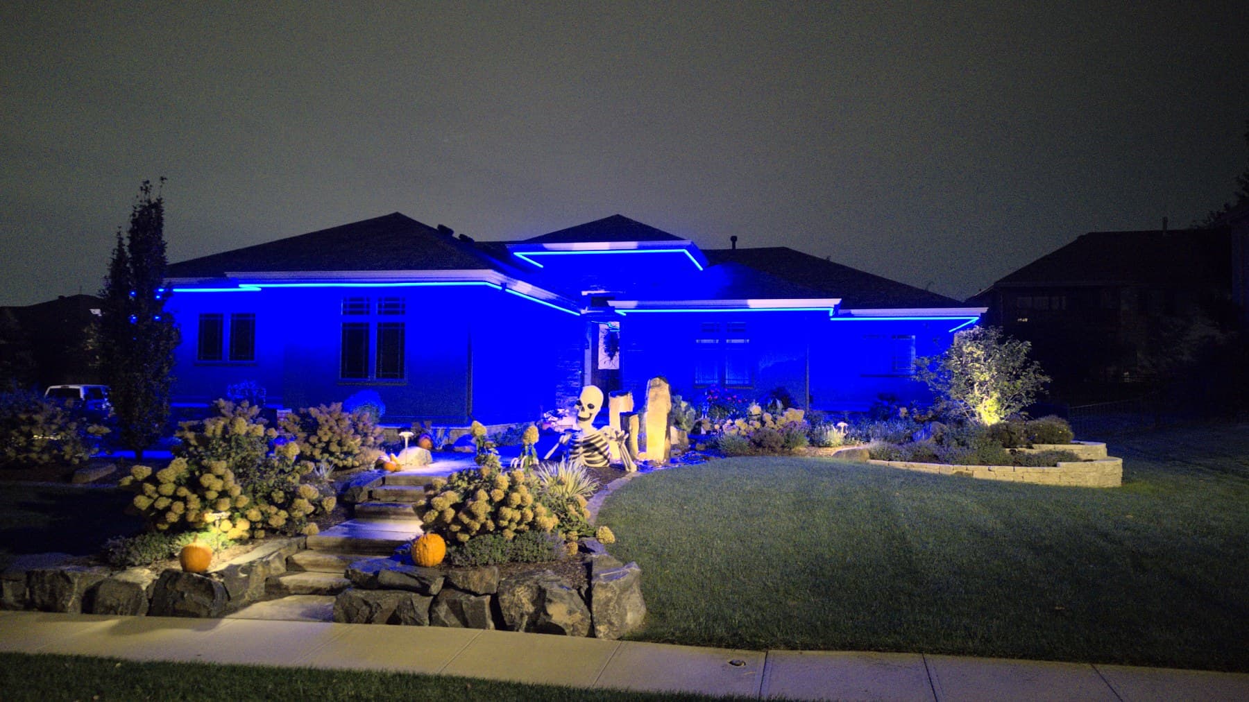 An Omaha ranch home in blue with a lit rock garden