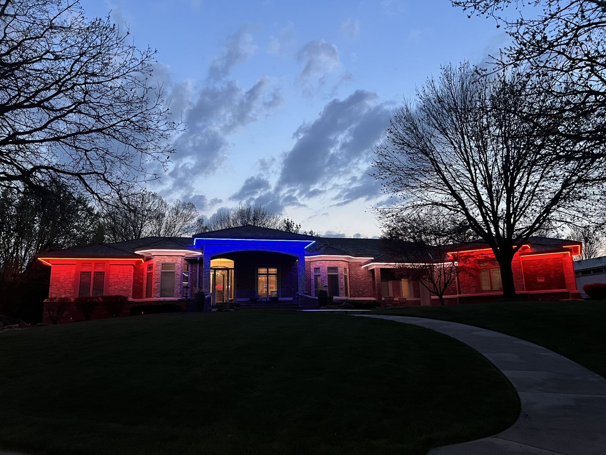 A long Omaha ranch at dusk in red, white and blue along a curved drive