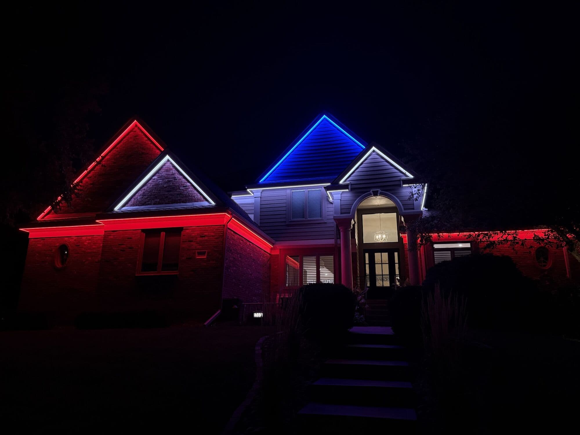A brick Omaha two-story with one gable in red, another in blue and white along the eaves