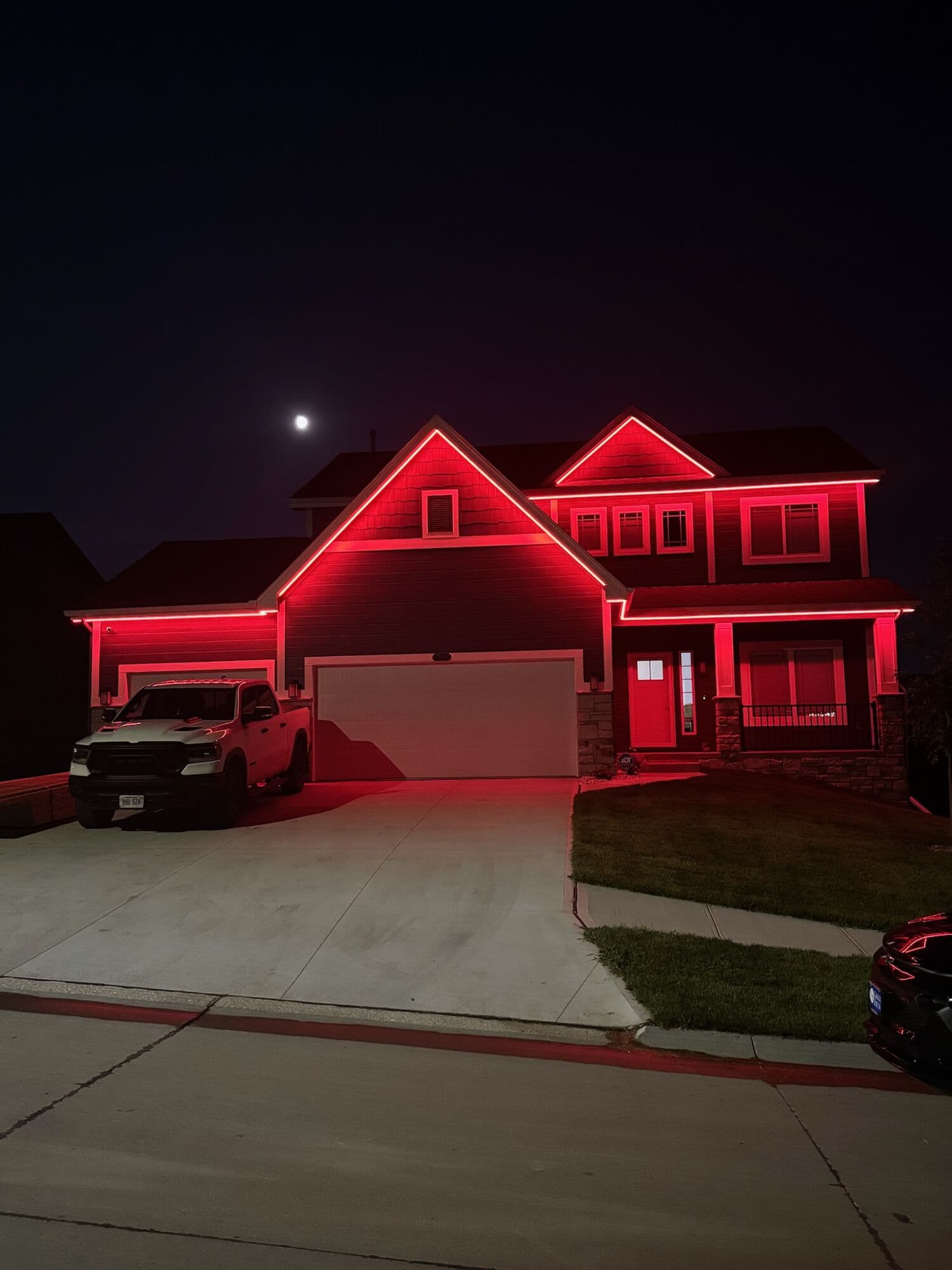 An Omaha two-story washed scarlet across the whole elevation under a moon