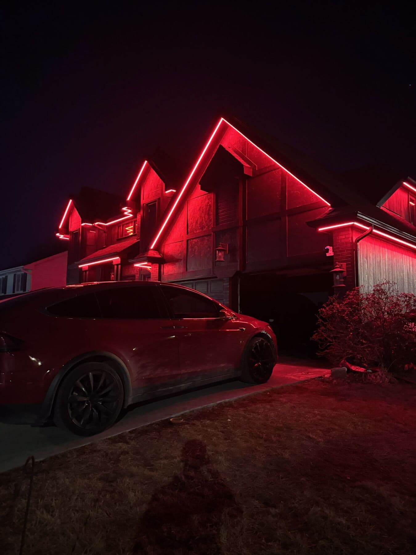 A deep red wash across the gable and eaves of an Omaha home with a car in the driveway lit red