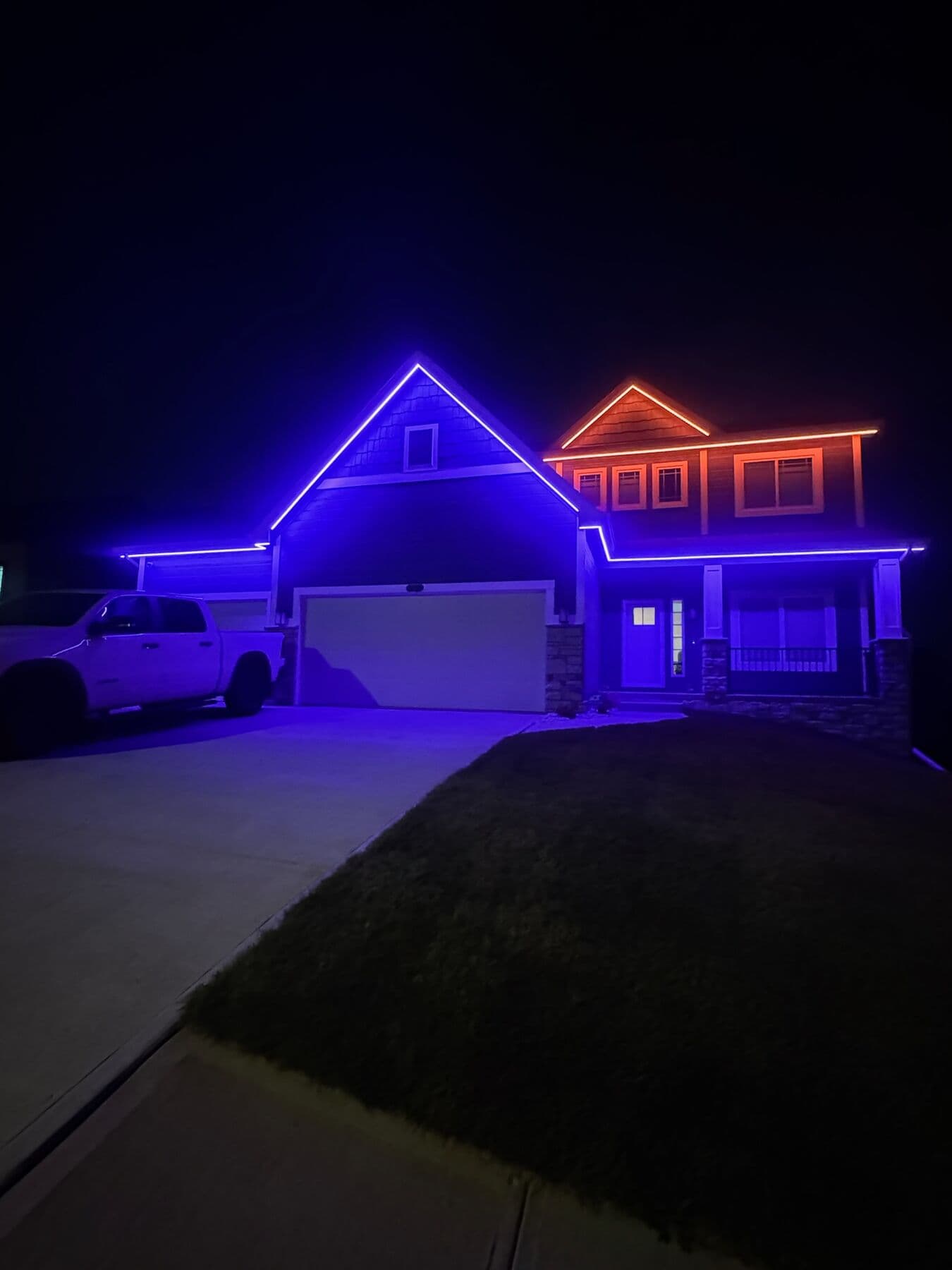 An Omaha two-story with the lower elevation in violet and the upper gable in orange, a truck in the drive