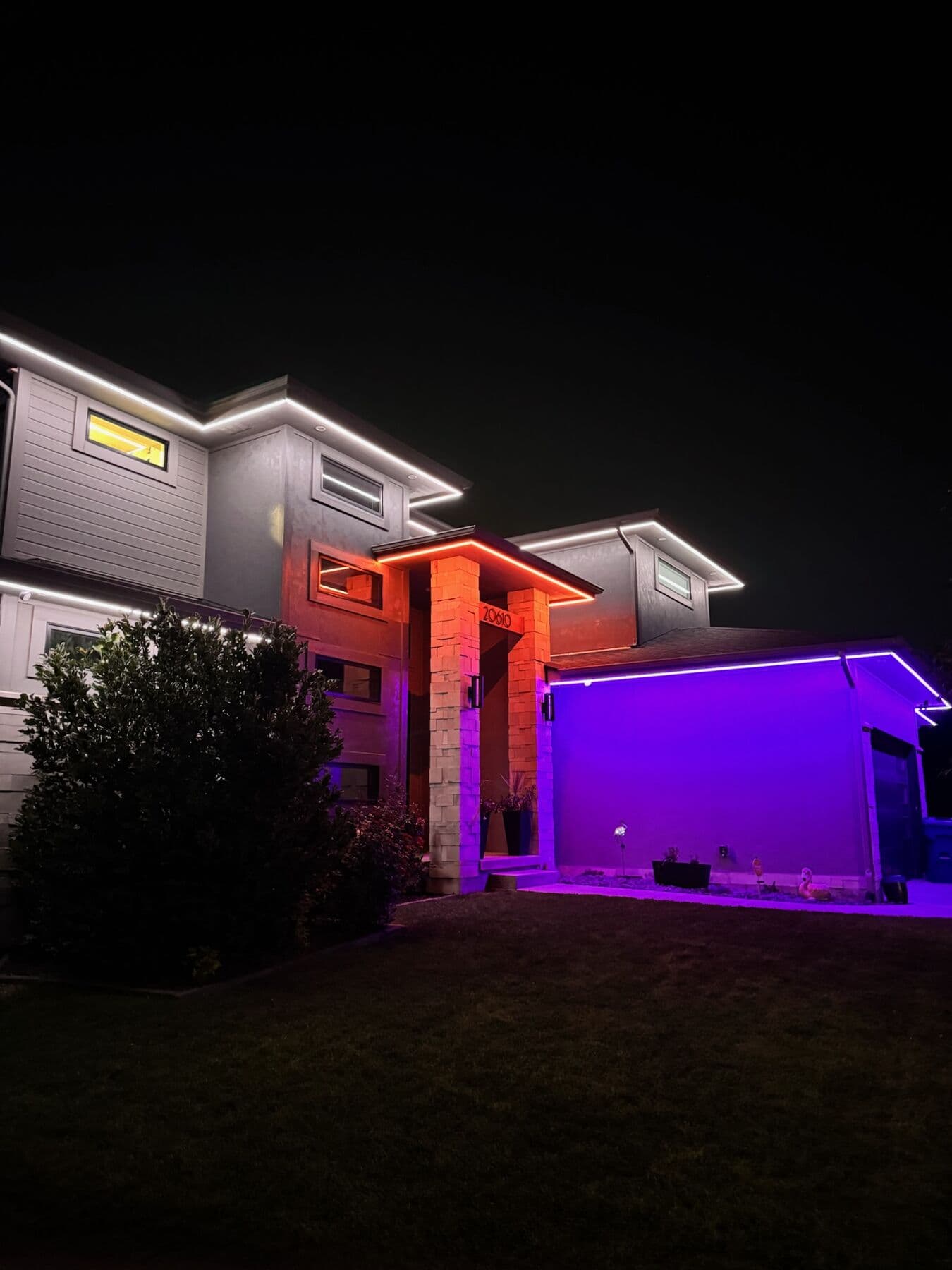 An Omaha two-story in orange and violet with a stone column washed amber for Halloween