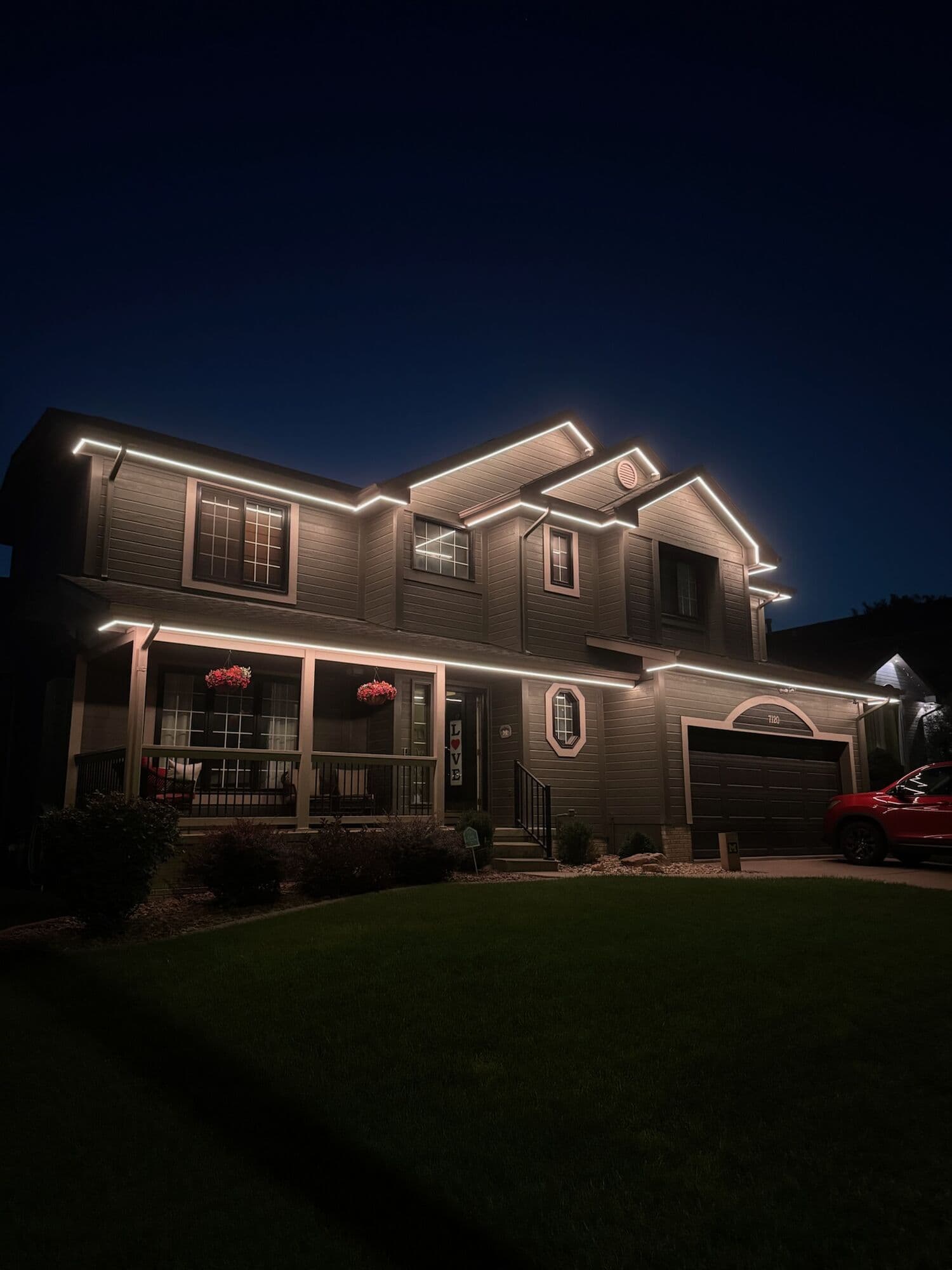 A craftsman Omaha home at blue hour, warm white along the porch roof and the upper gables