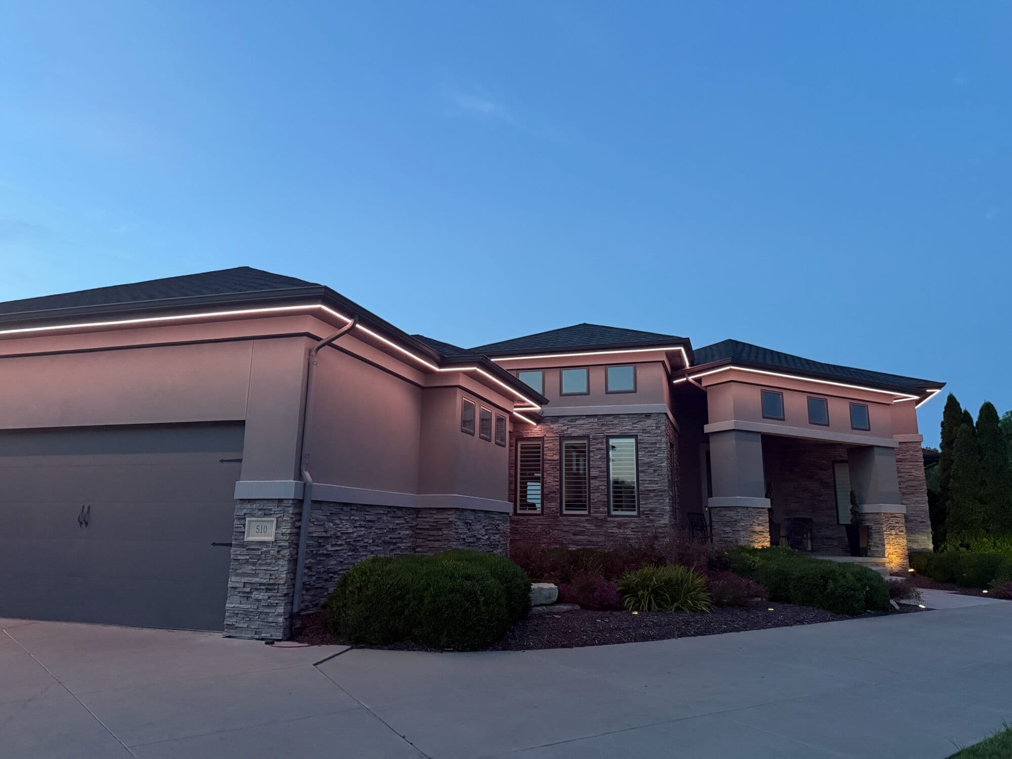 A stucco and stone prairie-style Omaha home at twilight with warm white under the eaves