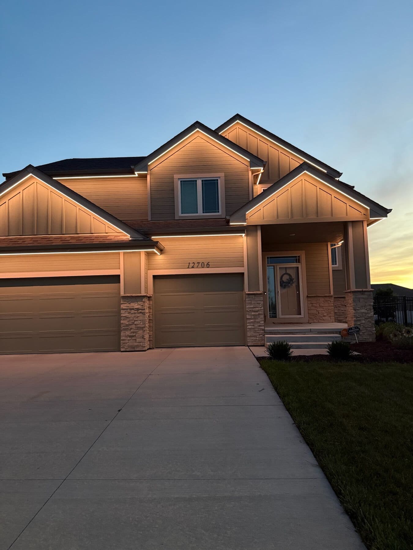 A tan Omaha two-story against a sunset with warm white along the gable and eave lines