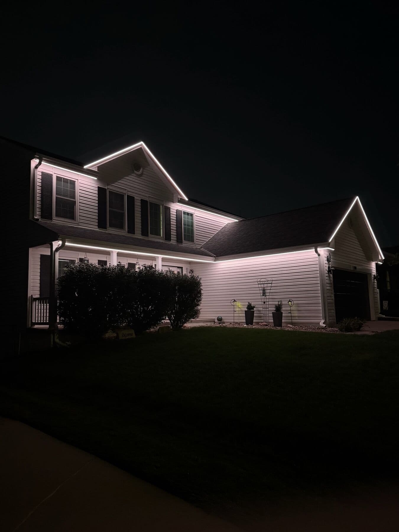 A white and gray Omaha two-story lit bright warm white along every roofline