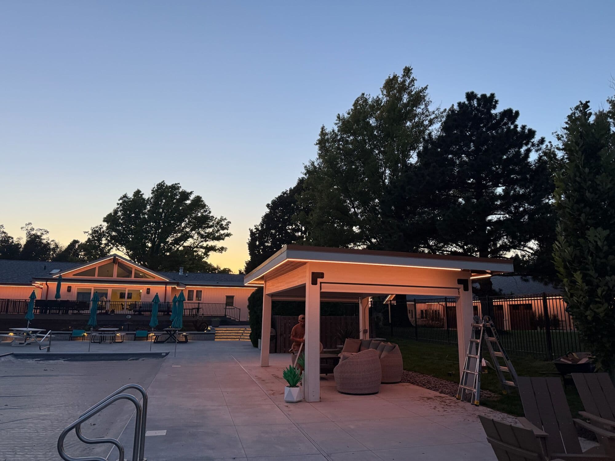 A ladder against a poolside pavilion at an Omaha home at dusk, the run being fixed along the beam