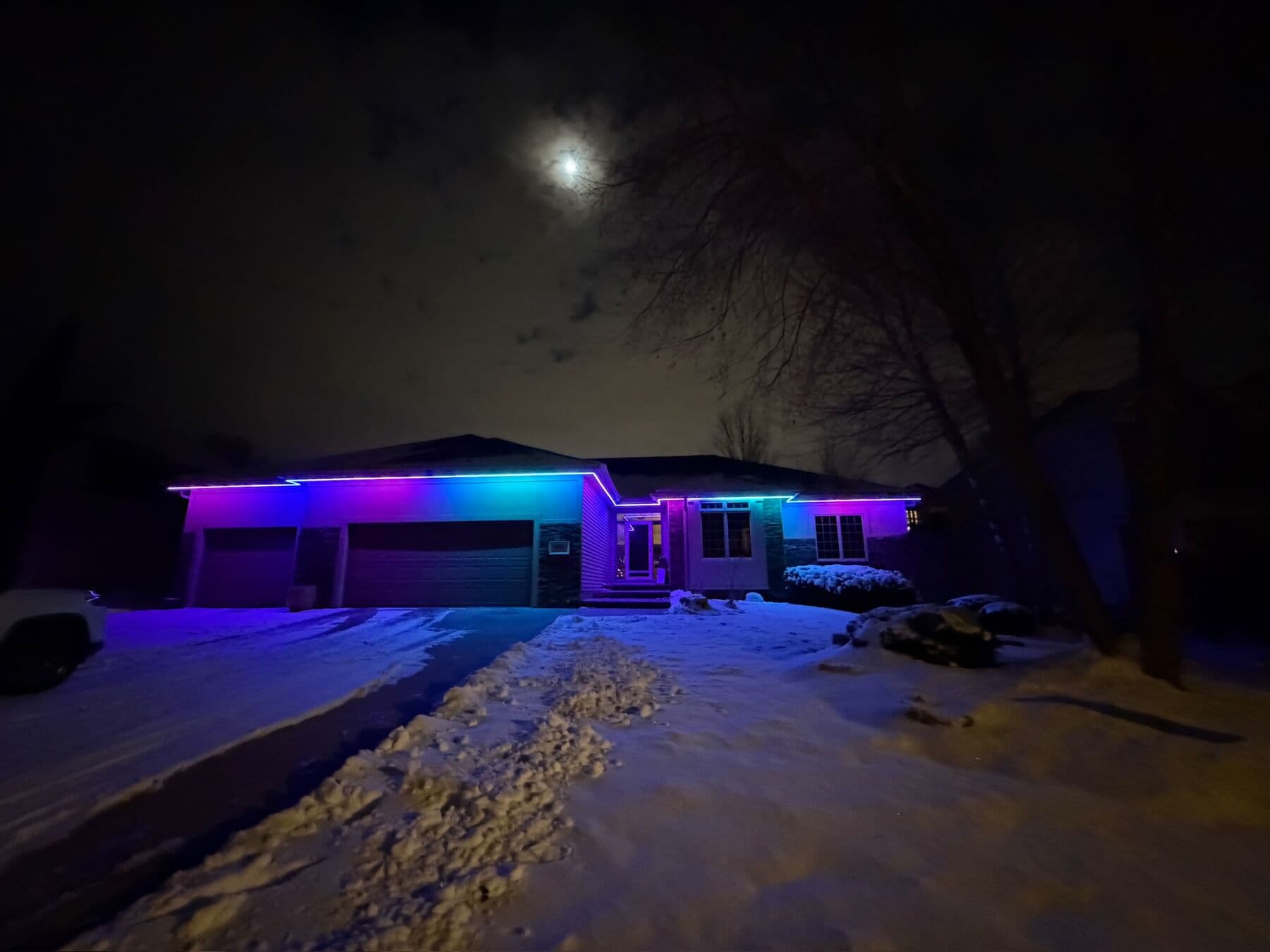 An Omaha ranch in snow with the roofline running through a gradient of colors under a moon