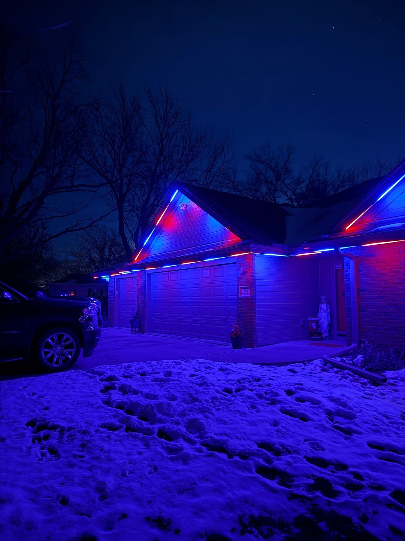 An Omaha home with red and blue gables and the snow in front of it lit blue